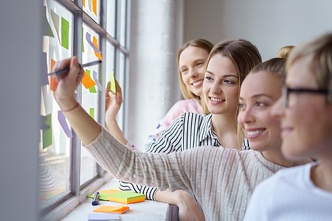 Vier junge Frauen die Klebezettel beschriften.