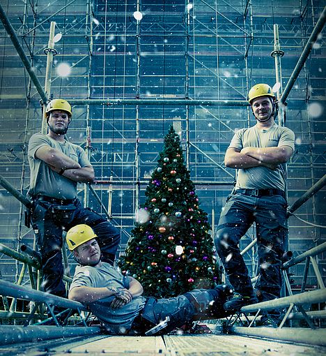 Gerüstbau-Azubis posieren vor einem Weihnachtsbaum