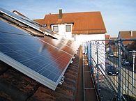 Ein Dach mit Photovoltaikanlage und Gerüst - Titelbild der Broschüre